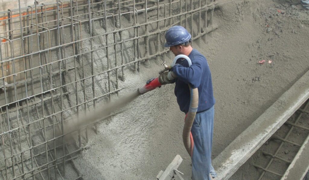 Worker spraying concrete onto rebar