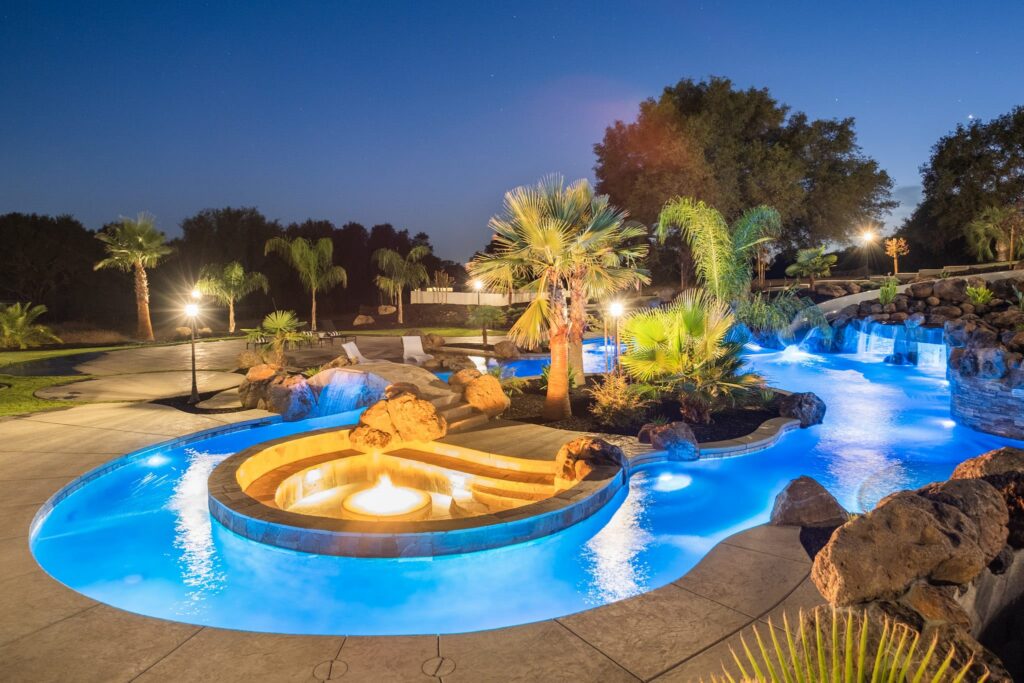 Illuminated pool with tropical landscaping.