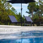 Poolside chairs under an umbrella.