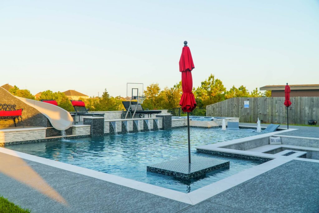 Modern pool with red umbrellas and slide